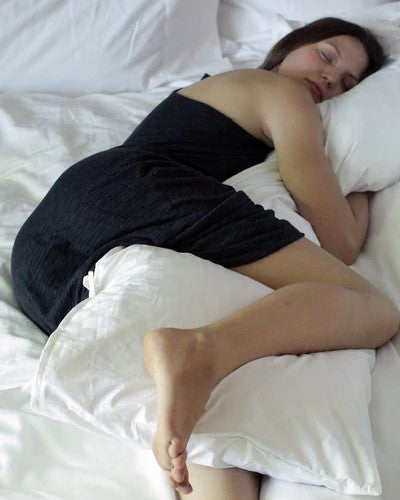 woman hugging pillow in bed