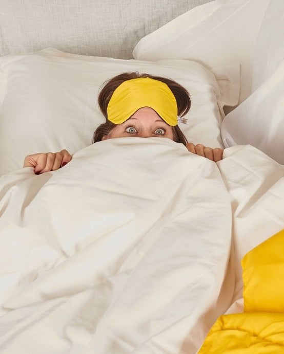 woman peeking from under bedcovers