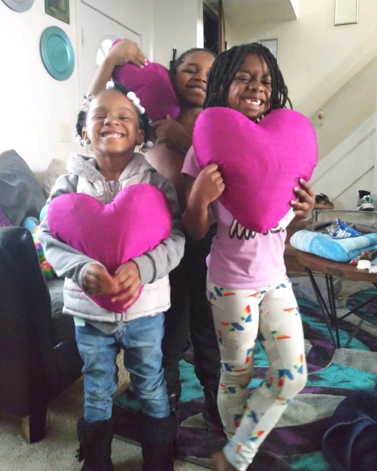 three girls hugging heart pillows