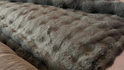 scotia sea faux fur throw in color gray folded across end of bed